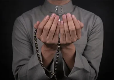 Muslim scholar making dua with hands raised in prayer